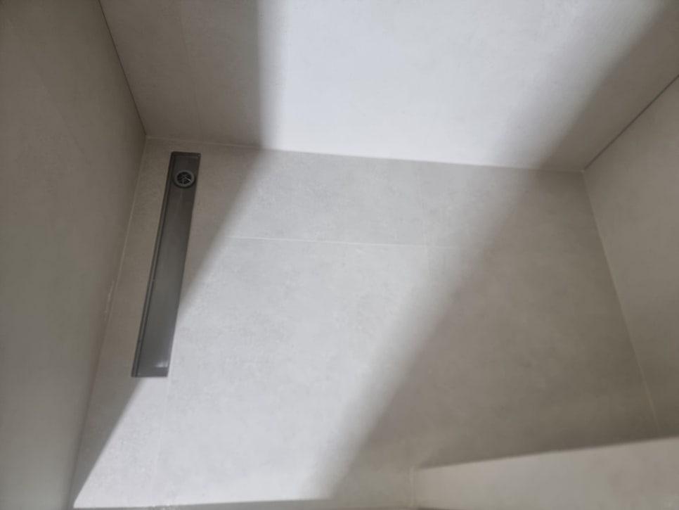 흰색 타일 벽면과 금속 장치의 접합부 근접 샷