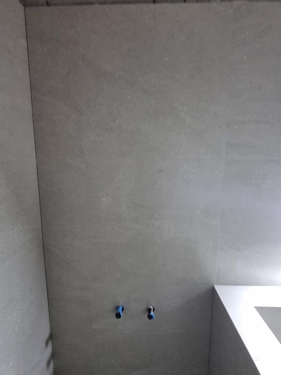 회색 벽면에 노출된 두 개의 파란색 배관 구멍