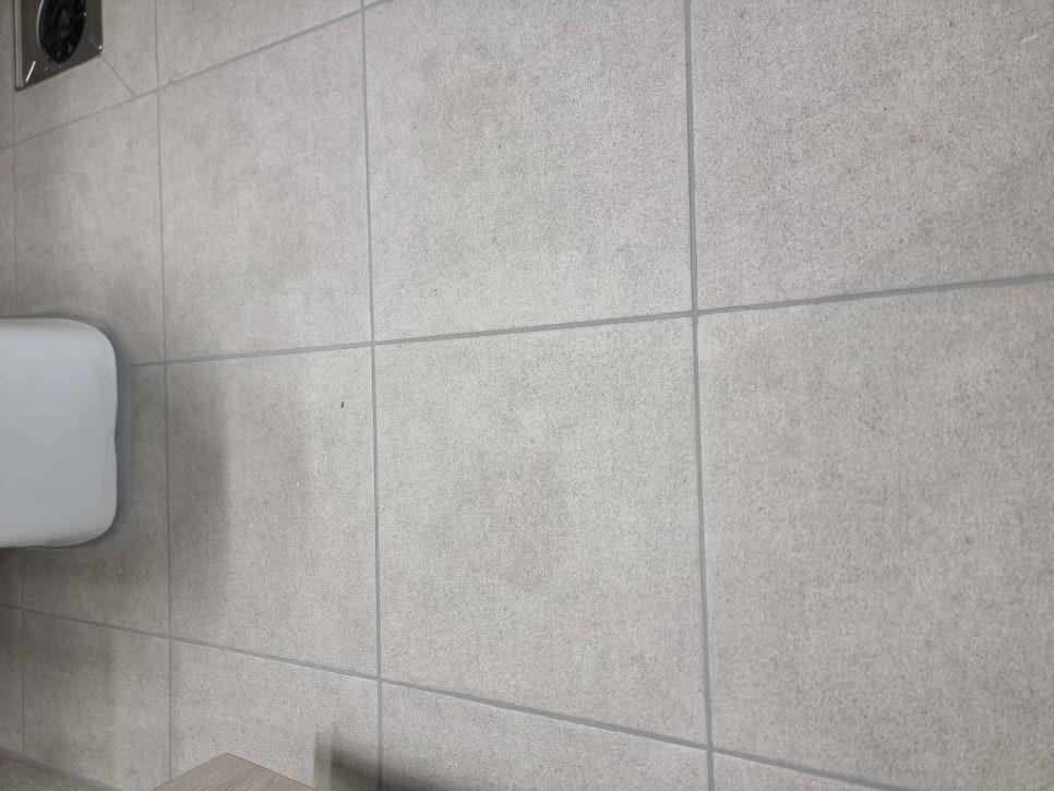 회색 타일 벽면과 흰색 세면대 일부