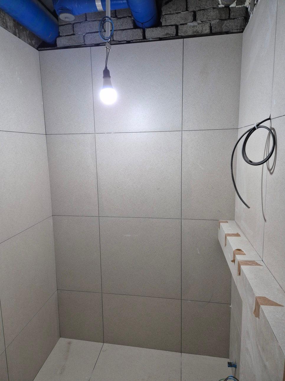 파란색 배관과 전선이 노출된 타일 벽면 공간