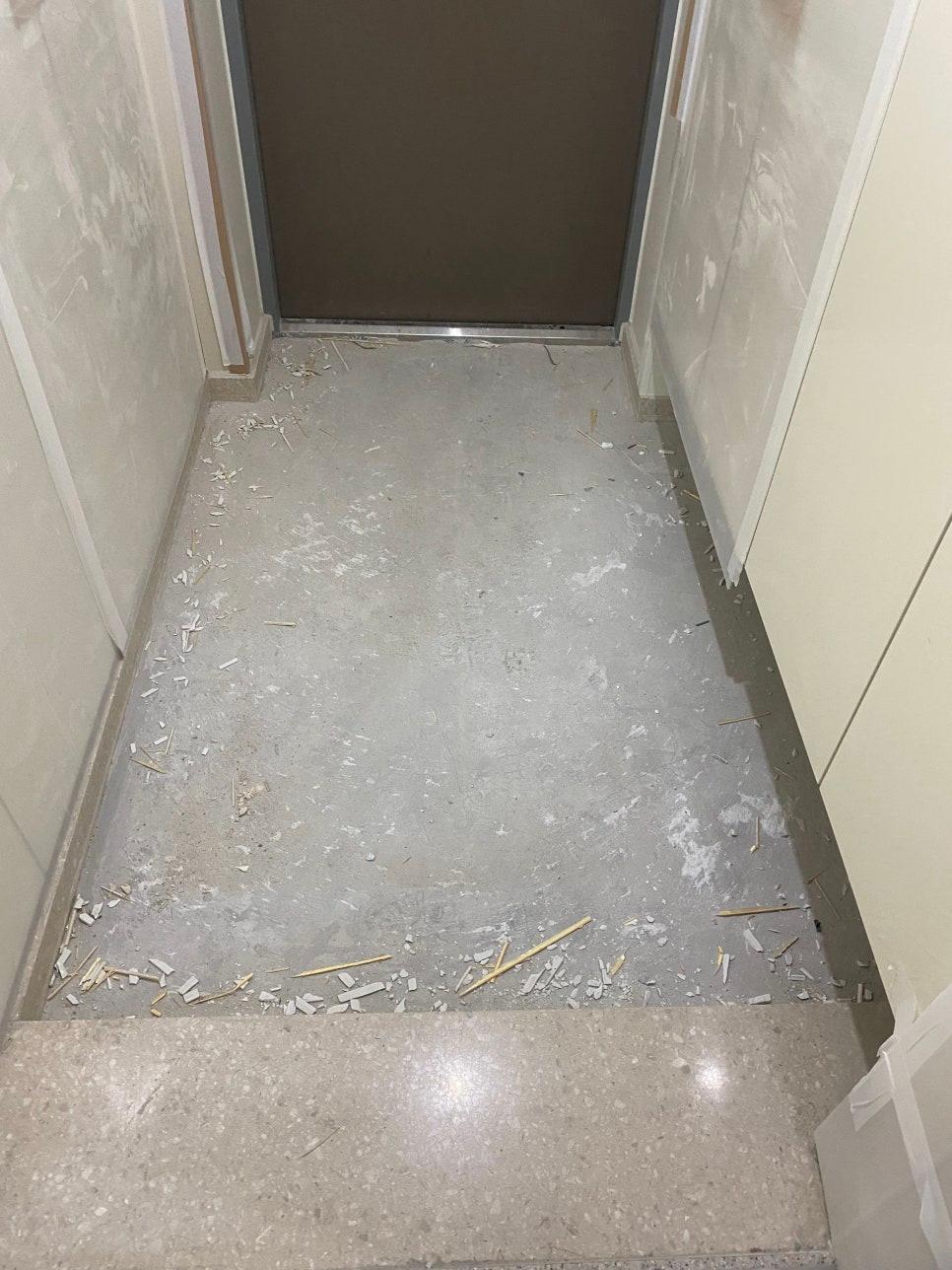 잔해물이 남은 바닥과 흰색 타일 벽면 마감