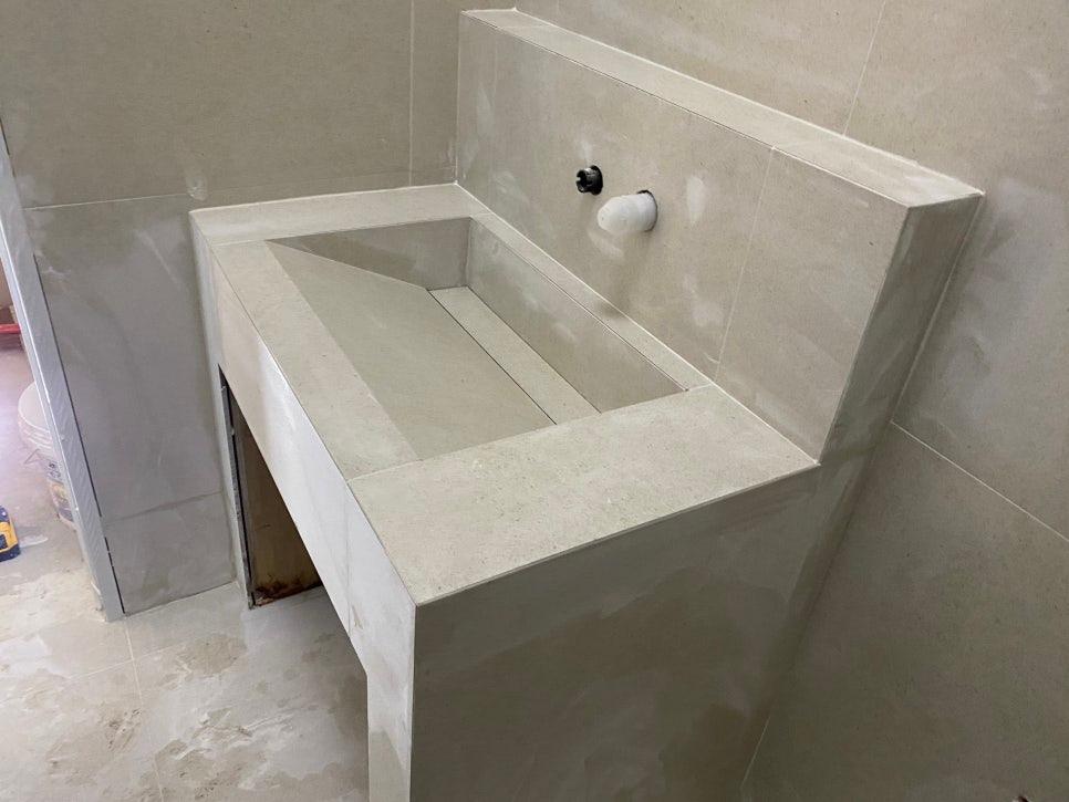흰색 타일 벽면과 콘크리트 세면대 구조물