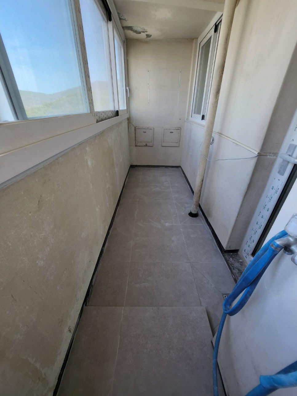 회색 타일로 마감 중인 창호 옆 발코니 공간