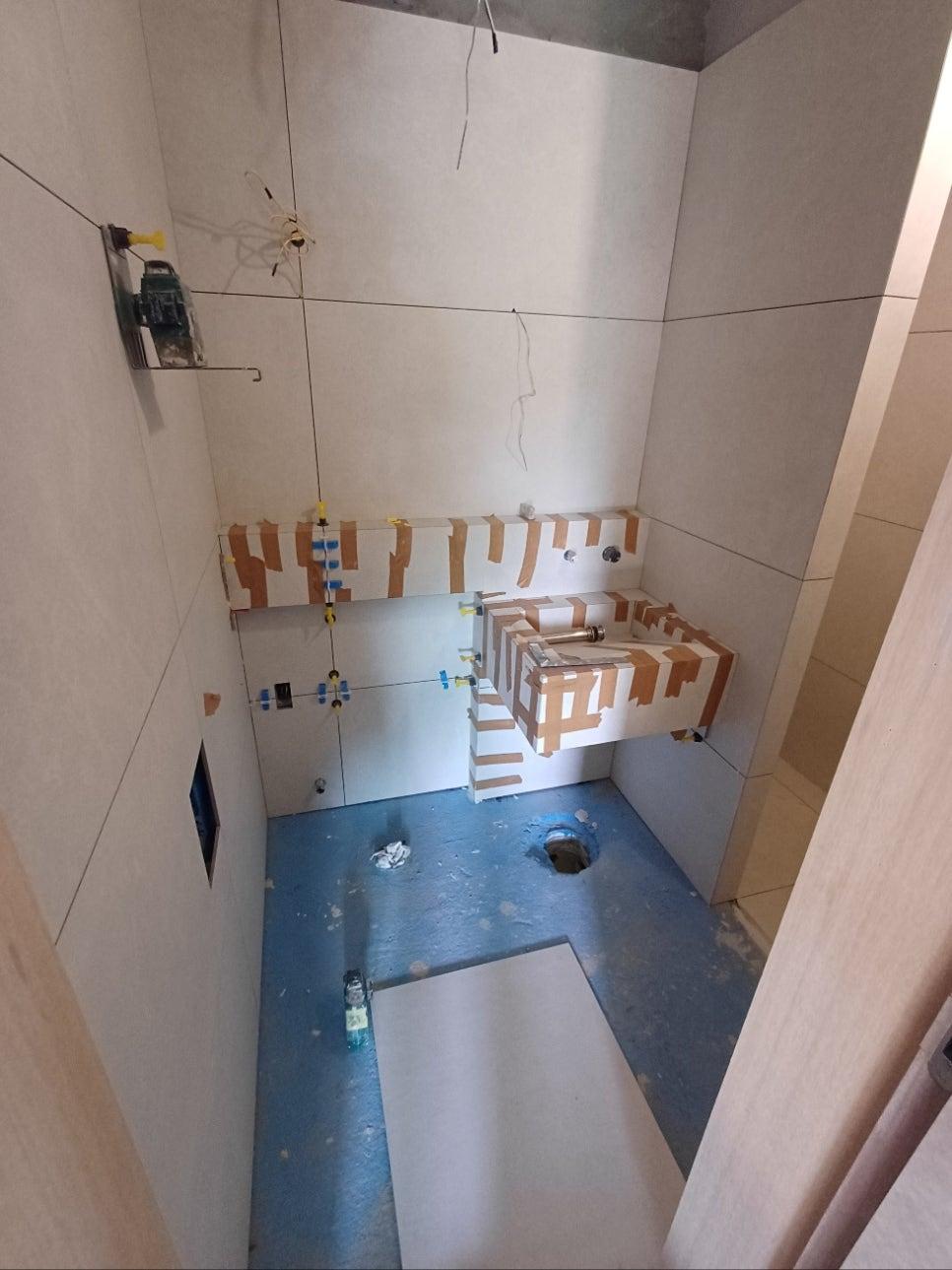 타일 부착 중인 벽면과 파란색 바닥 보호재