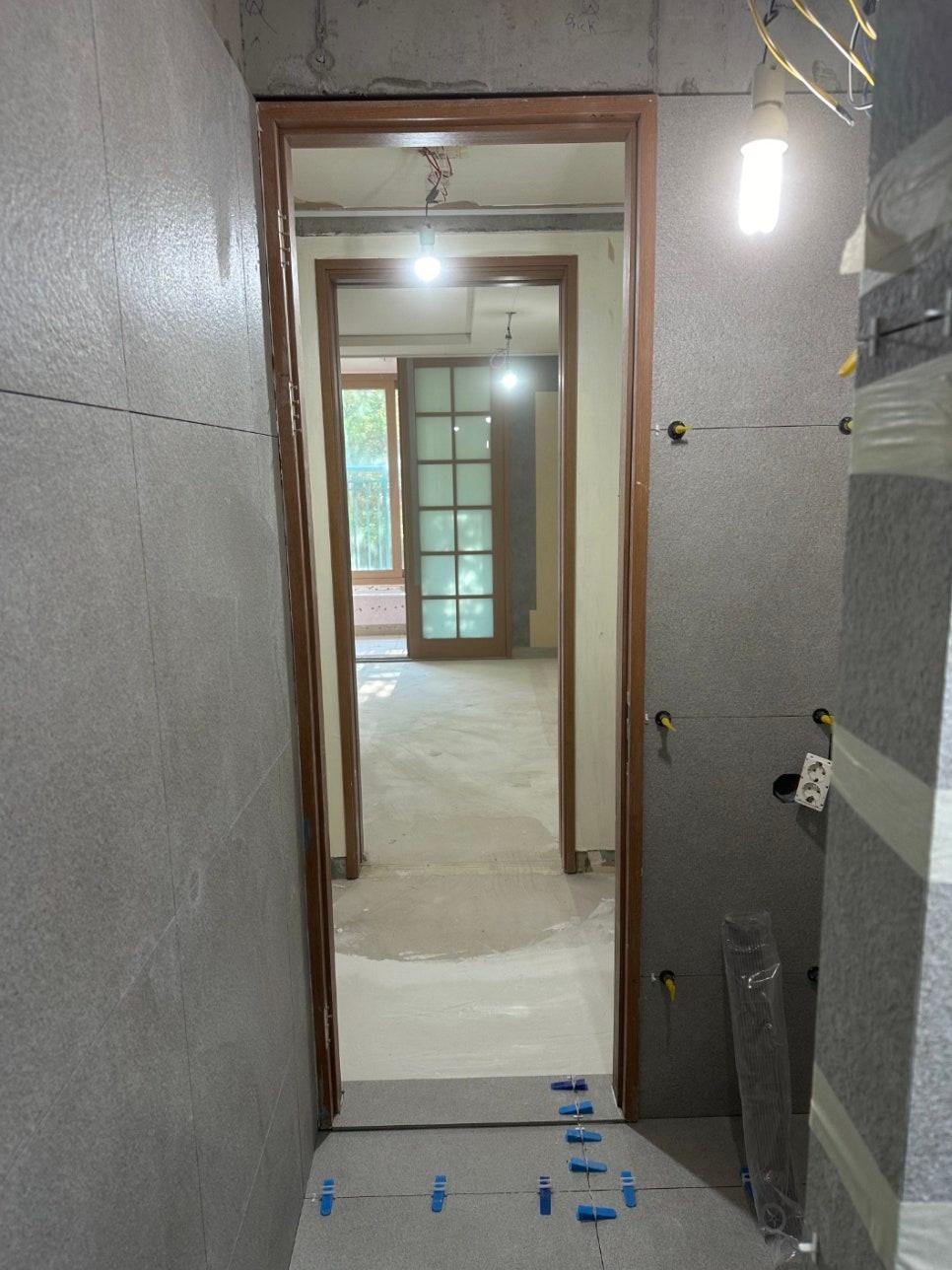 회색 타일 마감과 전선이 노출된 복도 시공 중 모습