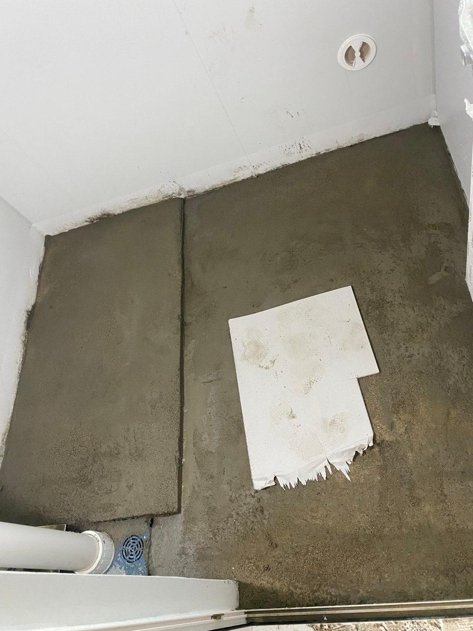 콘크리트 바닥과 배관 구멍이 보이는 벽면