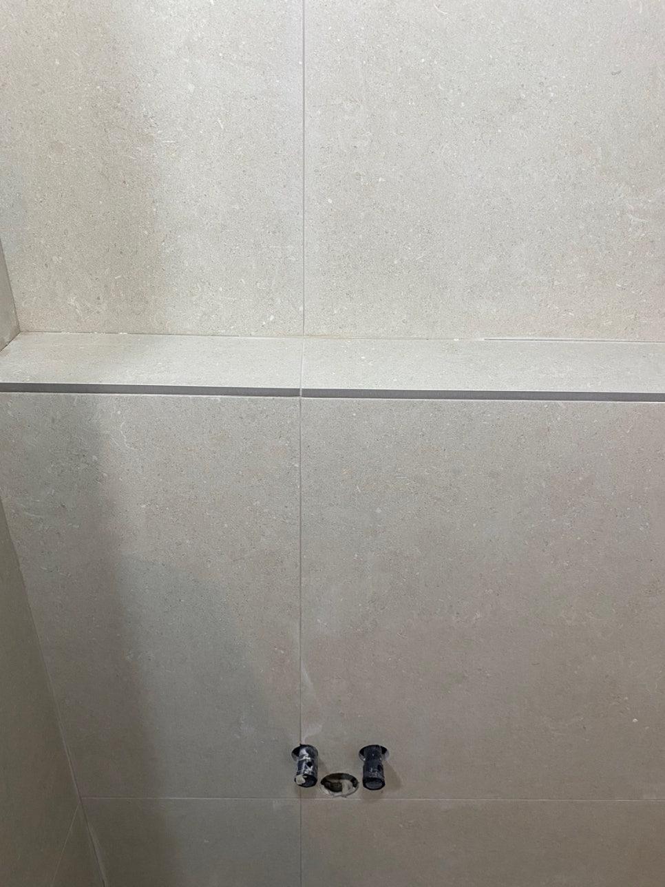 벽면 타일에 설치된 검은색 배관 부품