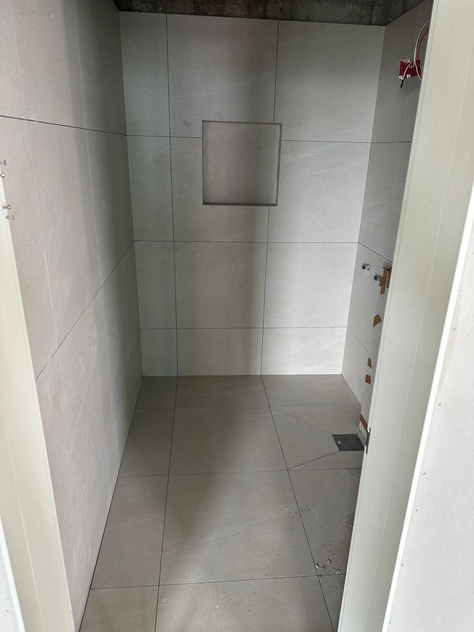 배관과 수전이 노출된 타일 시공 중인 벽면