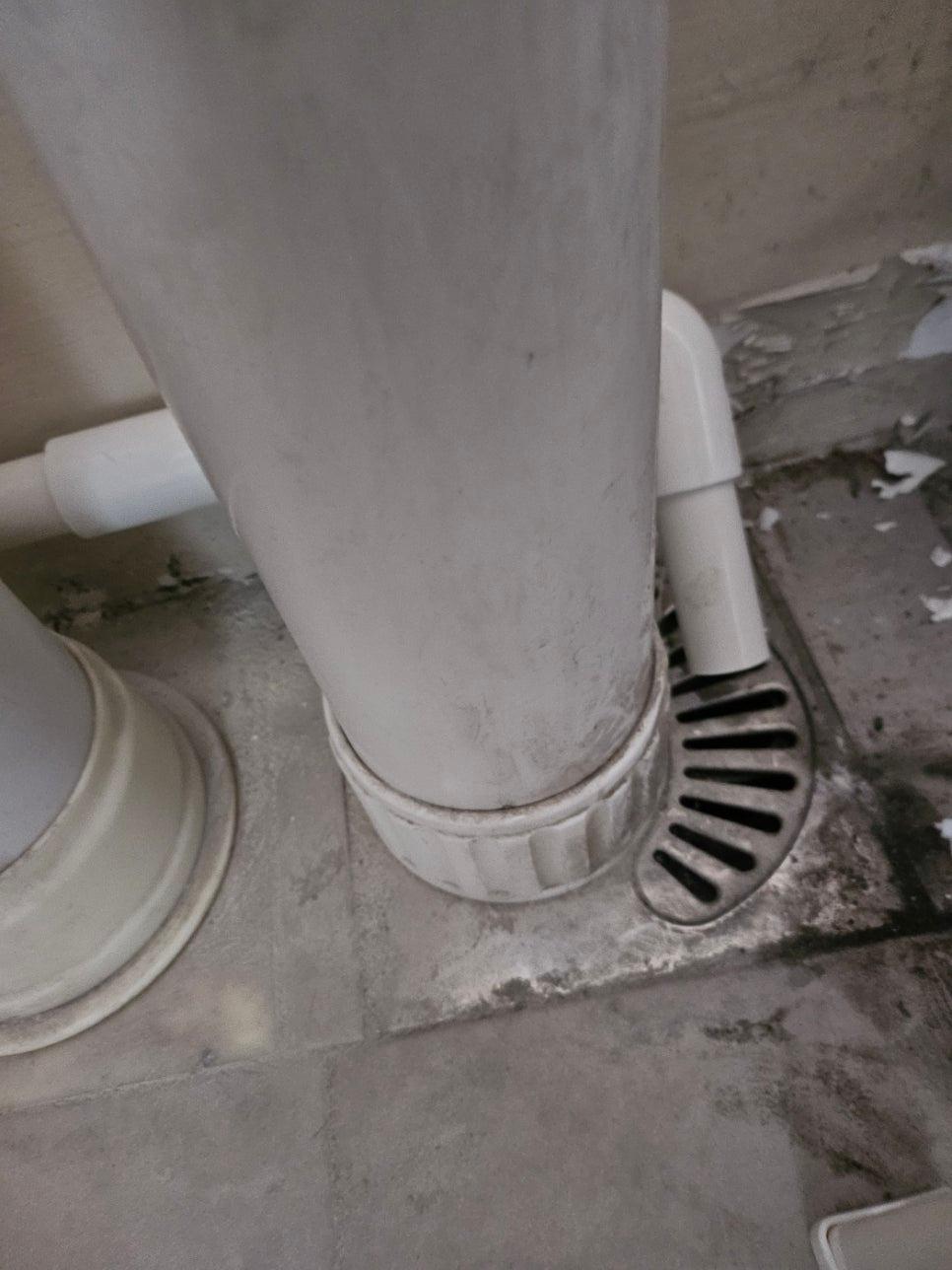 벽면에 설치된 흰색 PVC관과 배수구