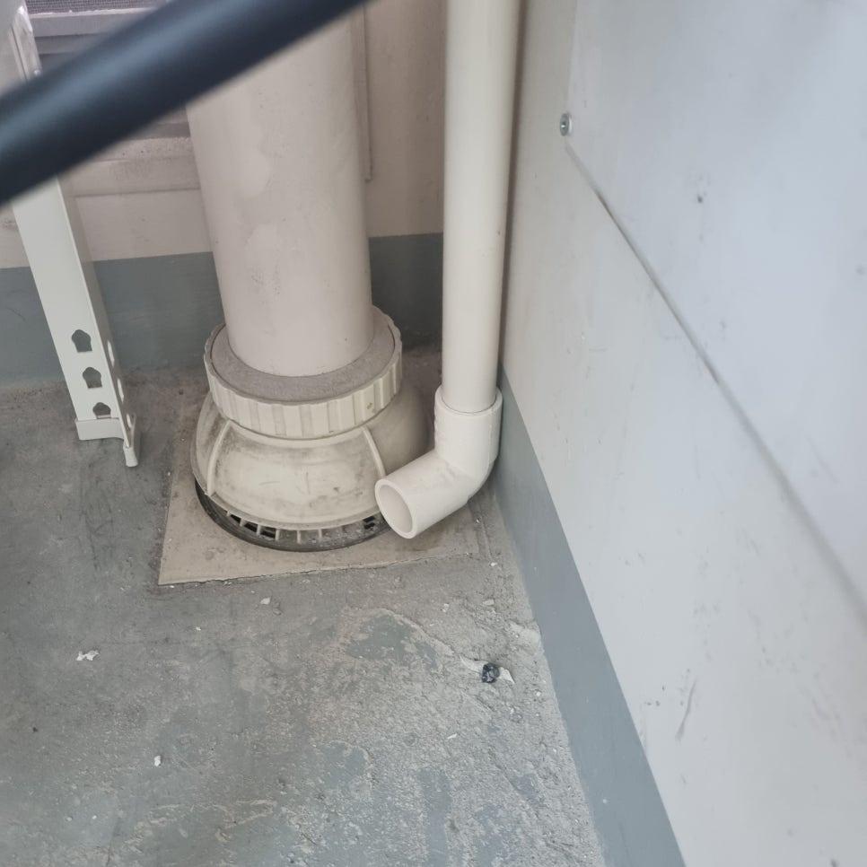 흰색 PVC 배관과 배수구, 벽면 및 바닥 접합부