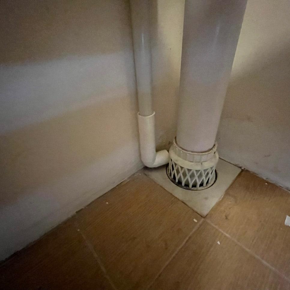 바닥 배수구와 연결된 흰색 PVC 배관