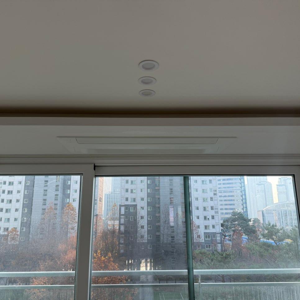 흰 벽과 천정 조명 너머로 보이는 외부 풍경