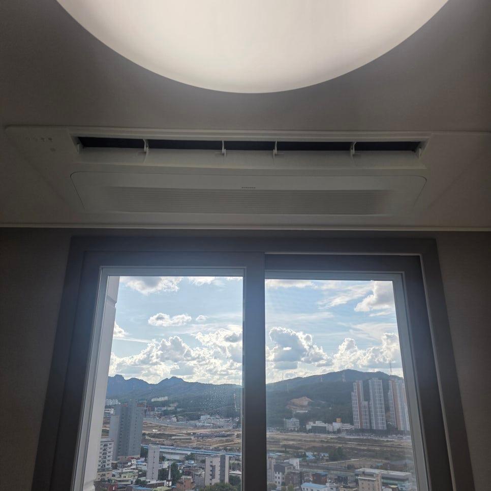 원형 조명과 에어컨이 설치된 천장과 창밖 하늘