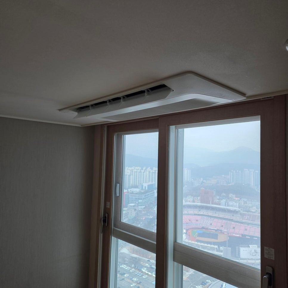 흰색 천정의 공기순환기와 우드톤 창호가 있는 실내