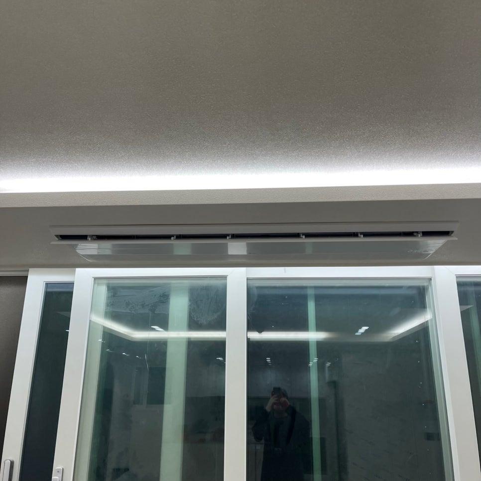 천장 LED 조명과 공기순환기가 설치된 유리문 앞 공간