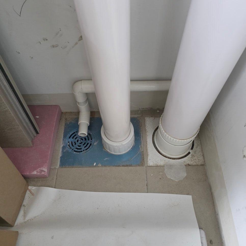 흰색 PVC 배관과 파란색 배수구가 설치된 벽면