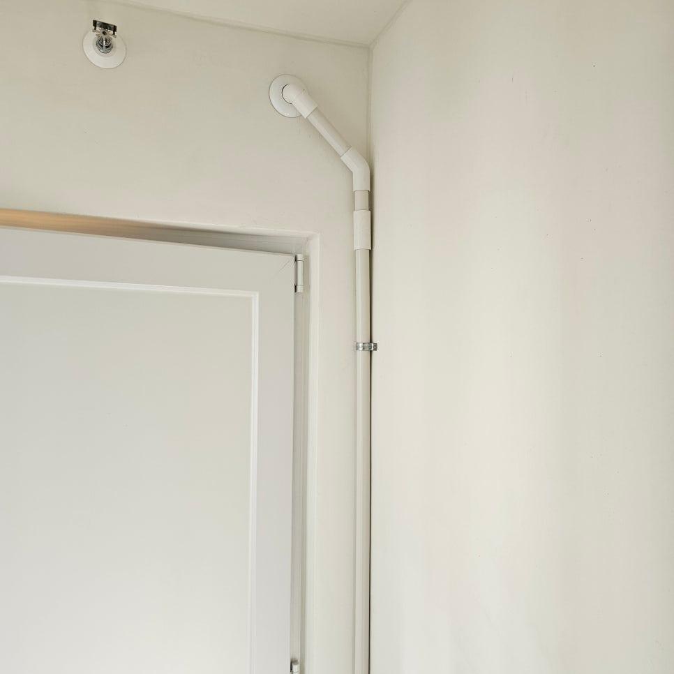흰 벽면에 설치된 흰색 PVC 배관과 라이트 장치