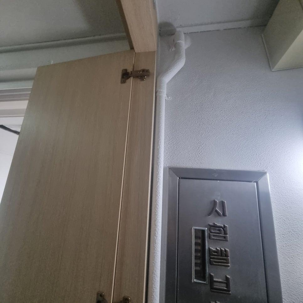 문짝과 벽면 사이를 지나는 흰색 배관