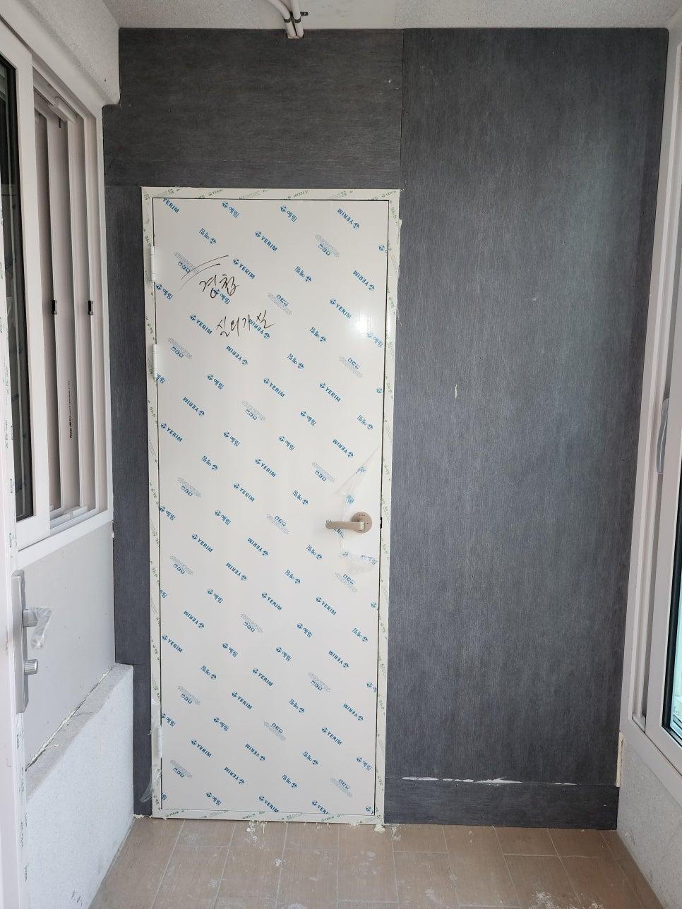 검은색 마감재 벽면과 보호필름이 붙은 현관문