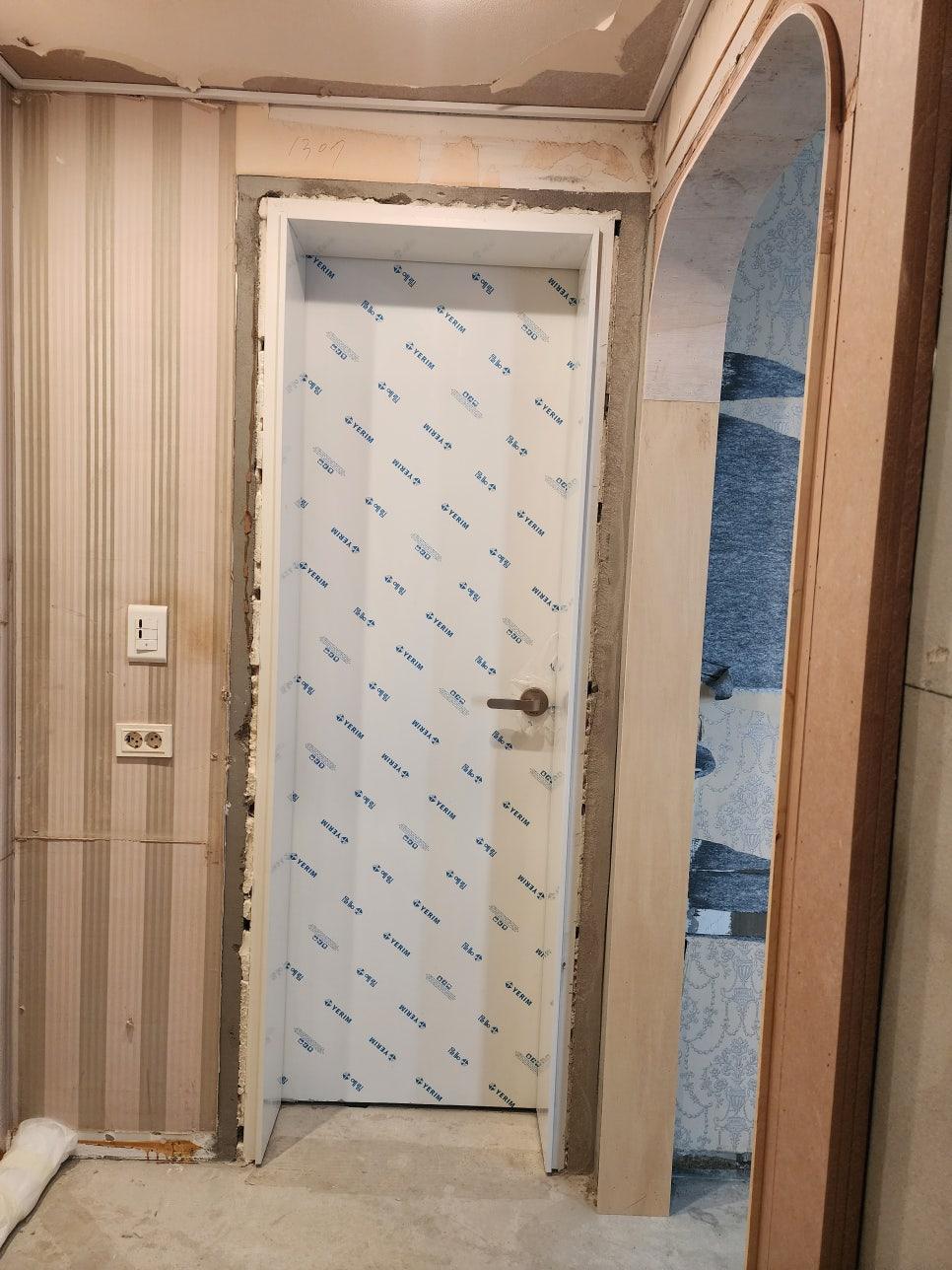 흰색 도배지와 스위치가 설치된 문 주변