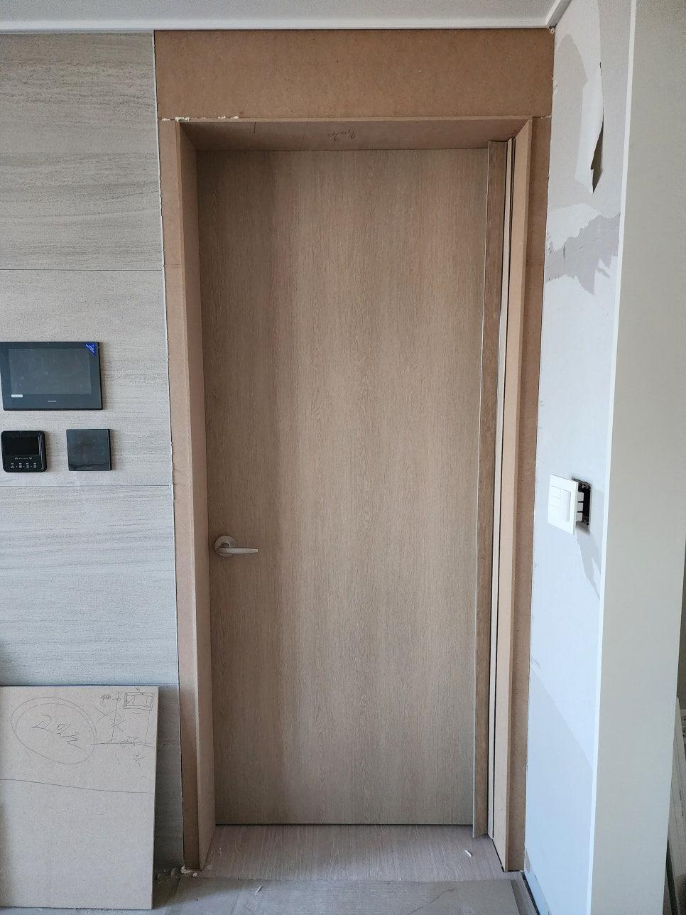 우드톤 도어와 타일 벽면이 보이는 현관 공사 현장