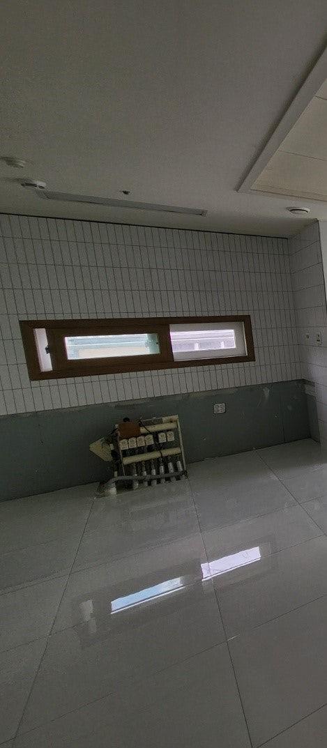 벽과 바닥에 화이트 타일을 시공 중인 모습
