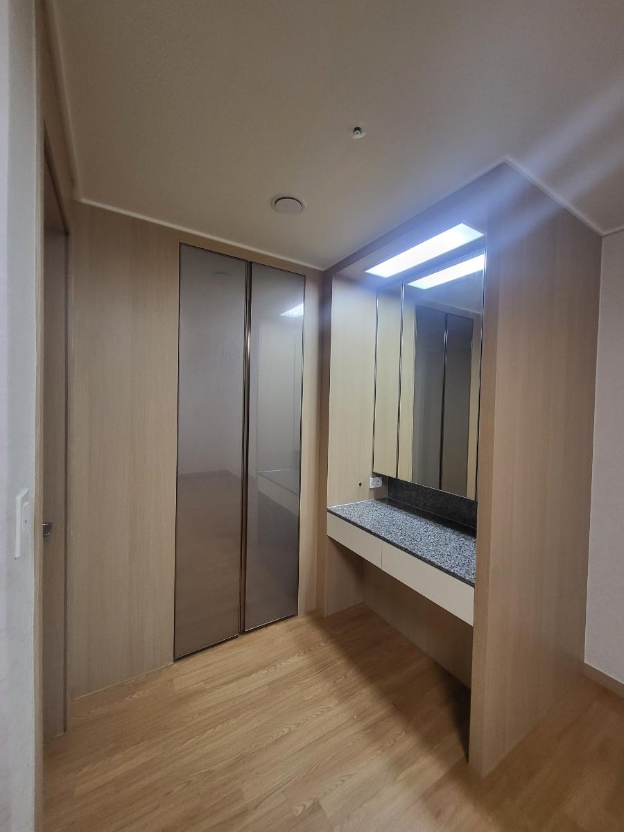 우드톤 마감과 유리 슬라이딩 도어가 있는 드레스룸