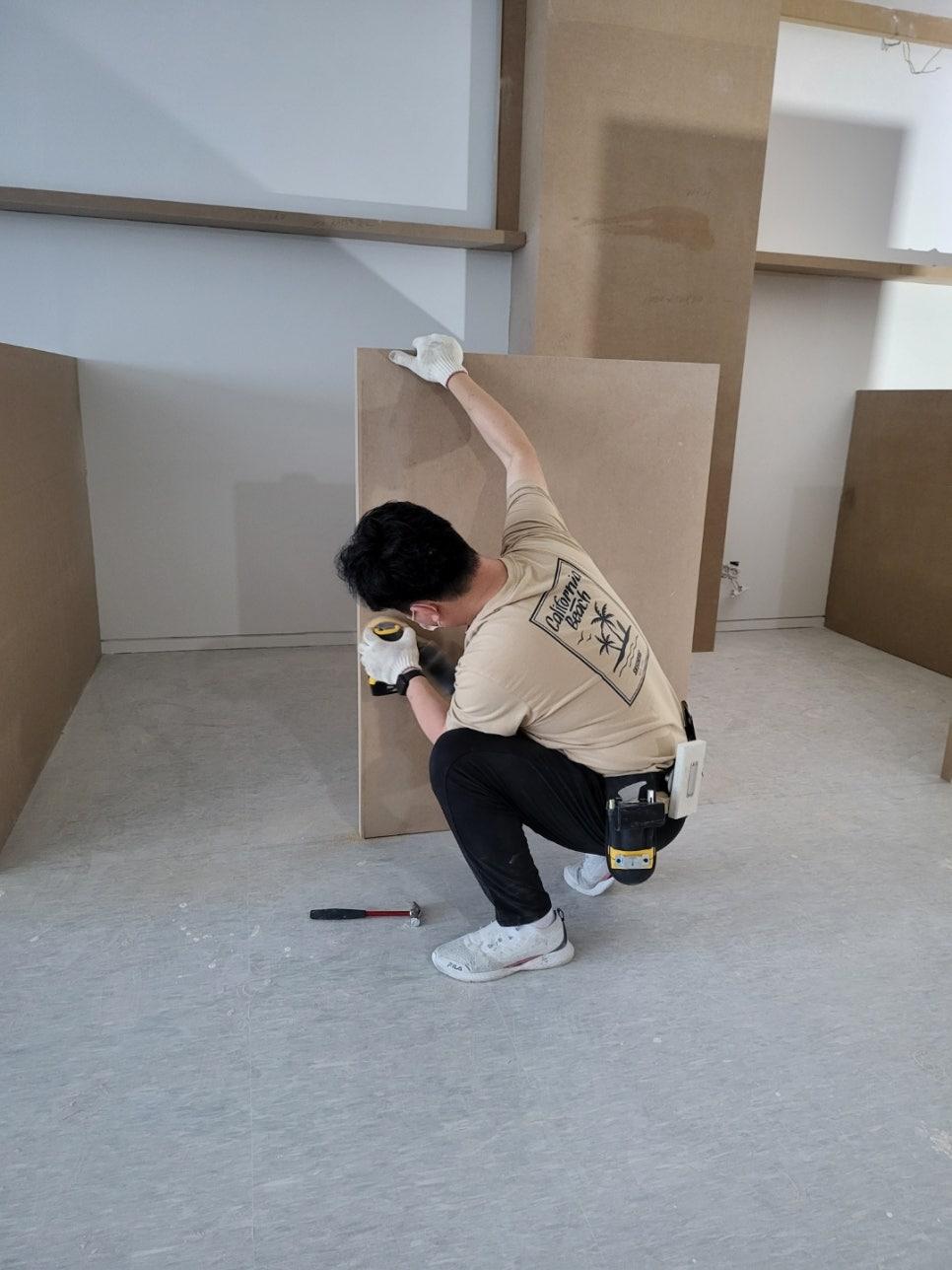 벽면에 보드를 설치하고 있는 작업자의 모습