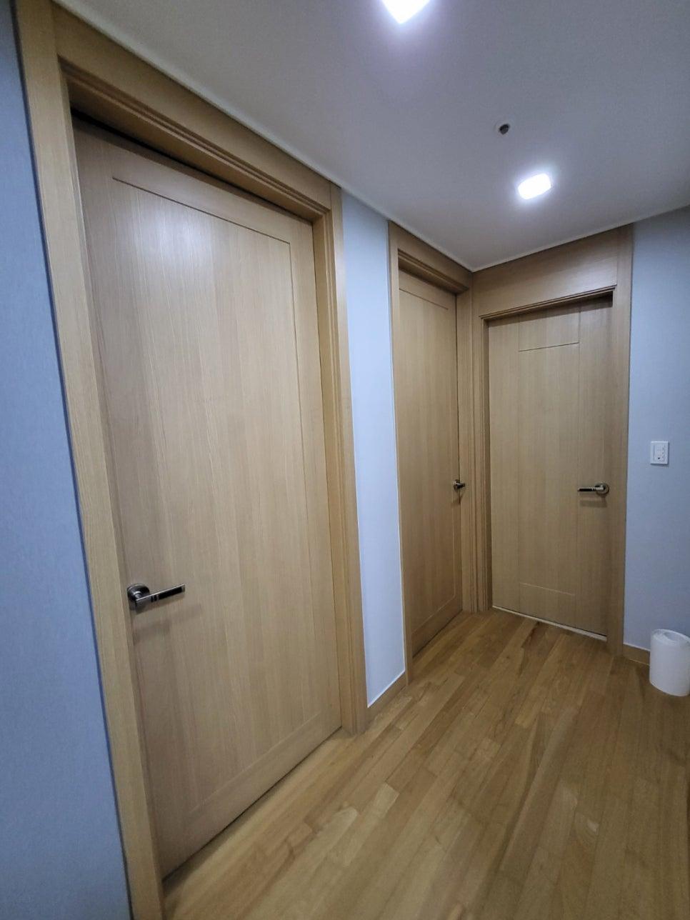 목재 바닥재와 회색 벽면이 이어지는 복도