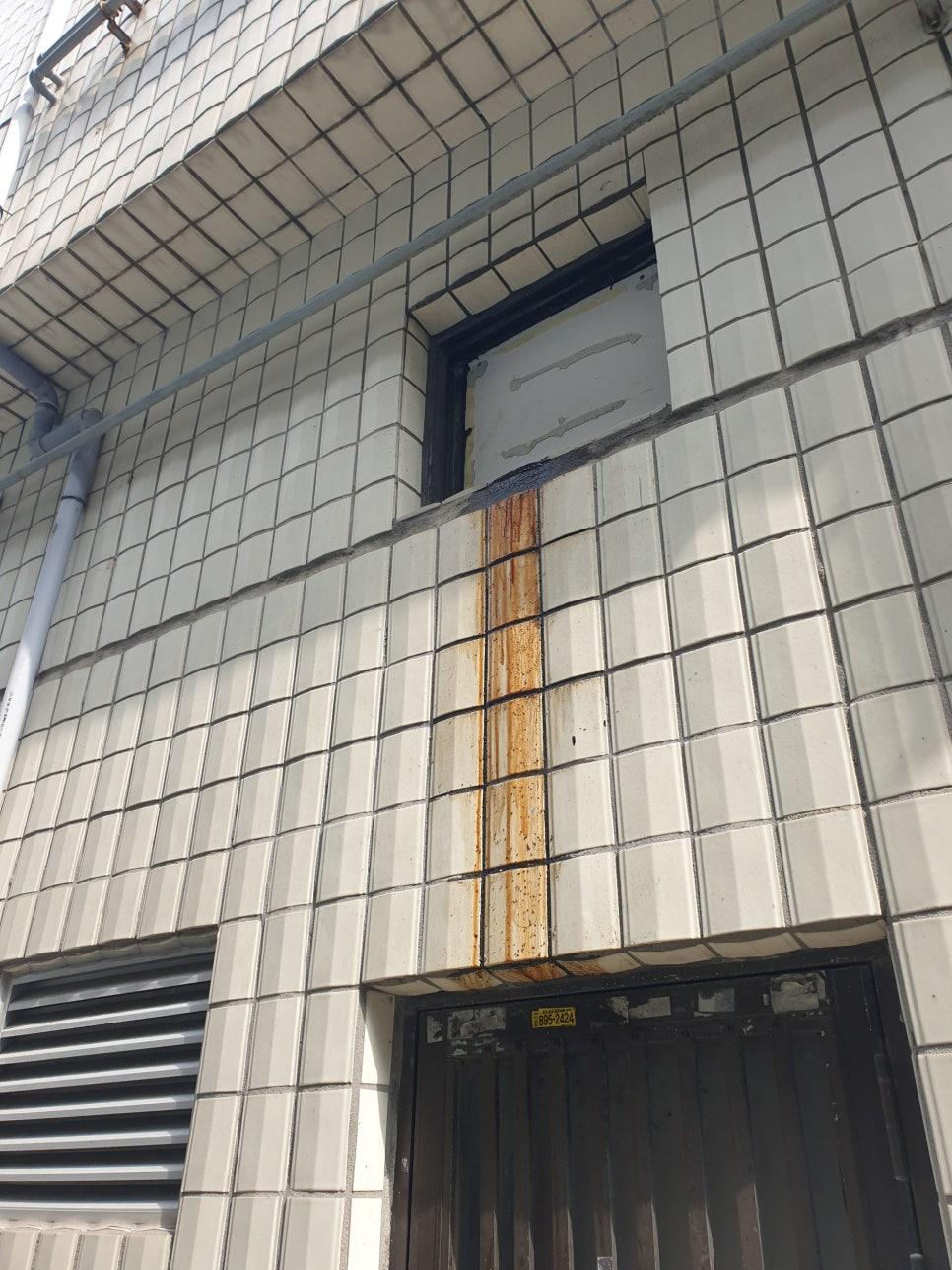 흰색 타일 벽면의 녹슨 금속 구조물 제거 과정