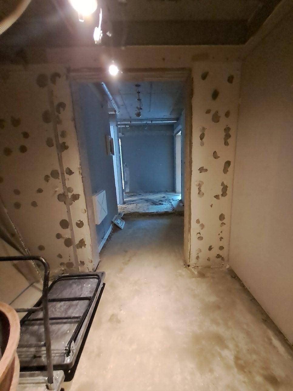 벽면에 흠집이 있고 바닥 마감이 되지 않은 복도