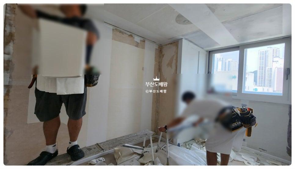창가 쪽에서 벽면 도배 작업을 이어가는 모습