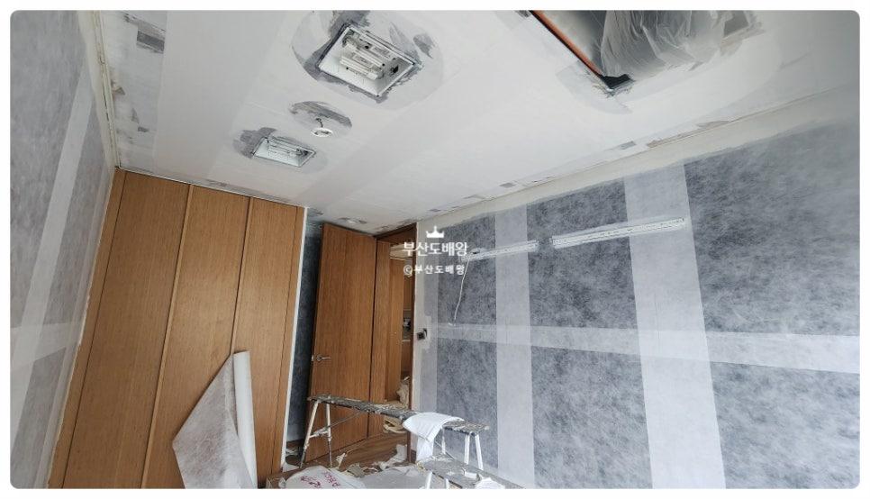 배관 구조가 노출된 천장과 테이프로 마감 중인 타일 벽