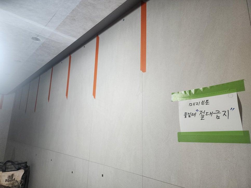 주황색과 녹색 테이프로 고정된 부직포 초배 작업