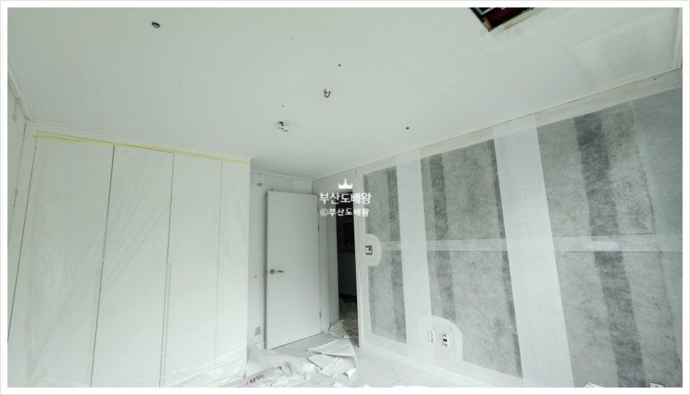 흰색 수납장과 문이 있는 공간의 도배 작업 과정