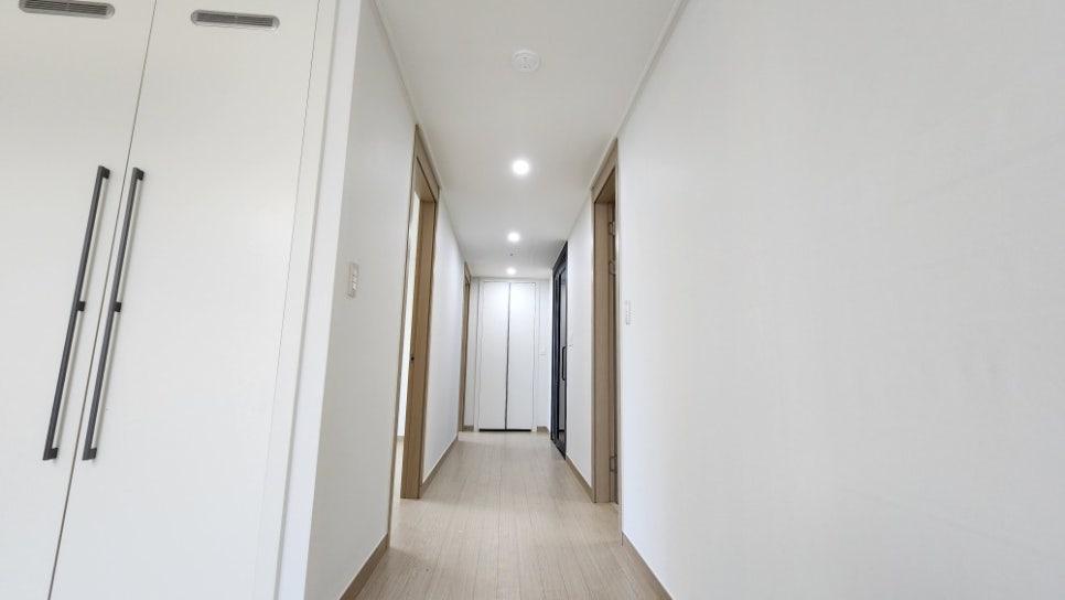 검은 핸들 수납장과 베이지색 문틀이 보이는 복도