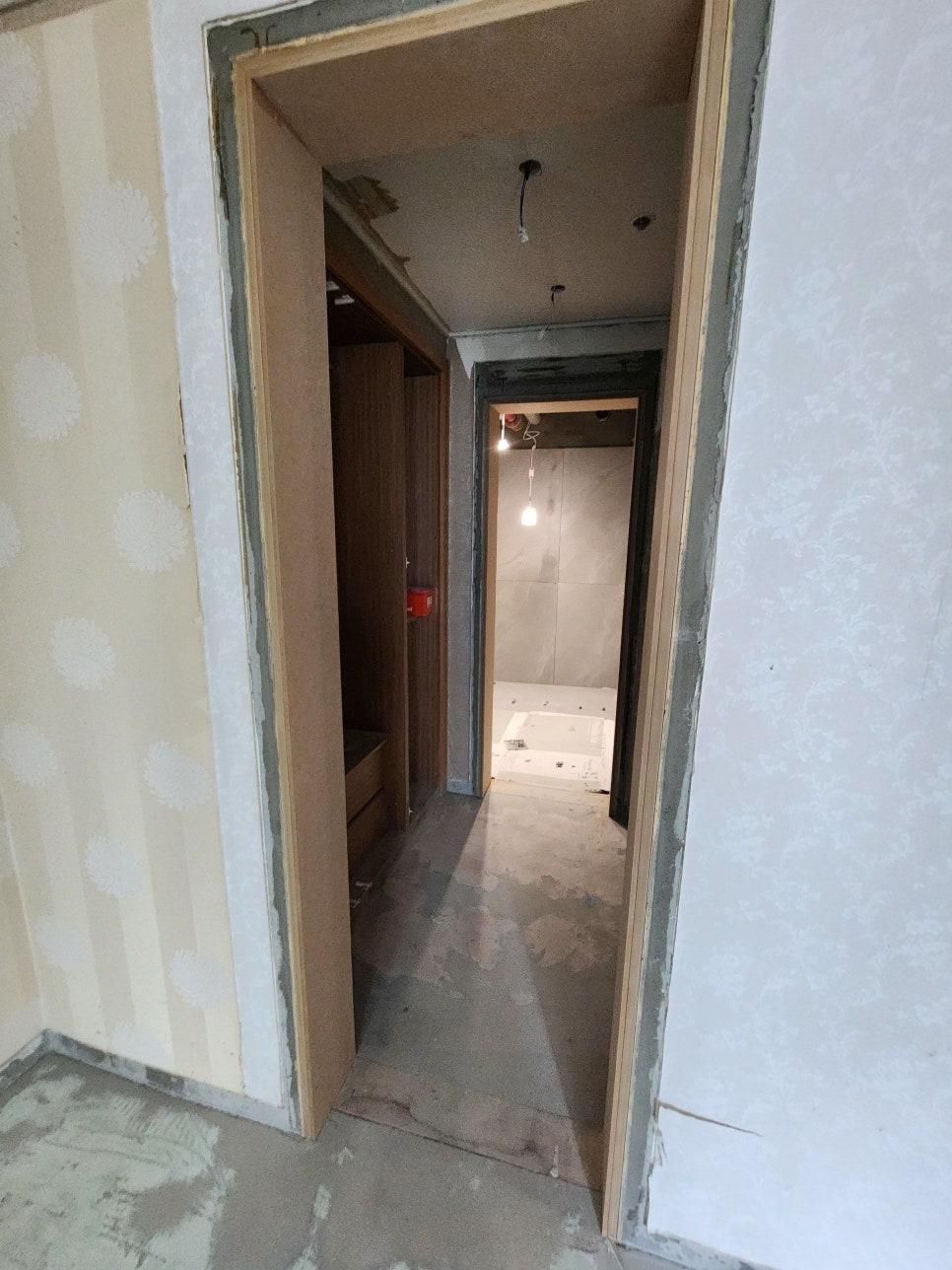 크림색 패턴 벽지가 부분적으로 시공된 복도