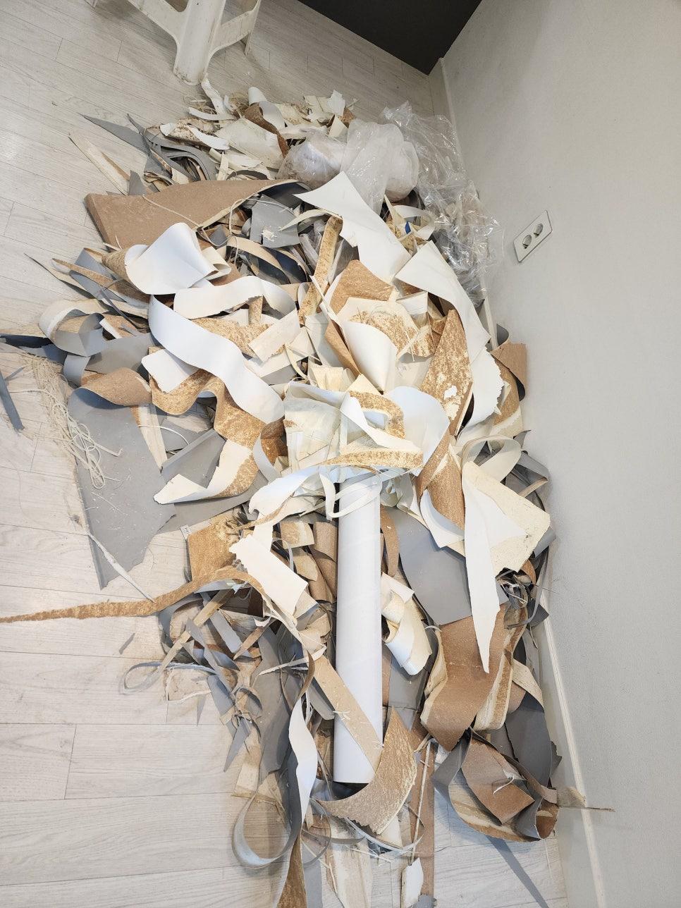 벽지 조각과 폐기물이 쌓여 있는 바닥 모습