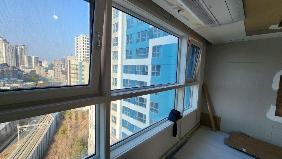 외부 풍경이 보이는 큰 창호와 도배 중인 벽면
