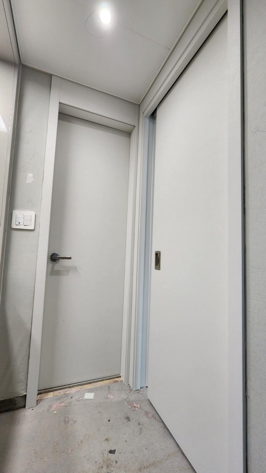 흰색 문과 스위치가 설치된 복도 작업 현장
