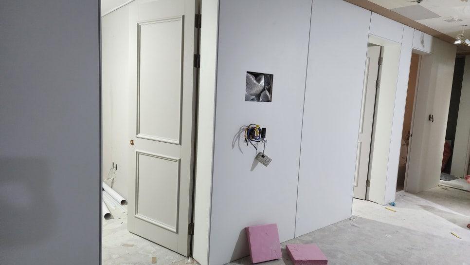 흰색 도어가 설치되고 전선이 노출된 복도 벽면