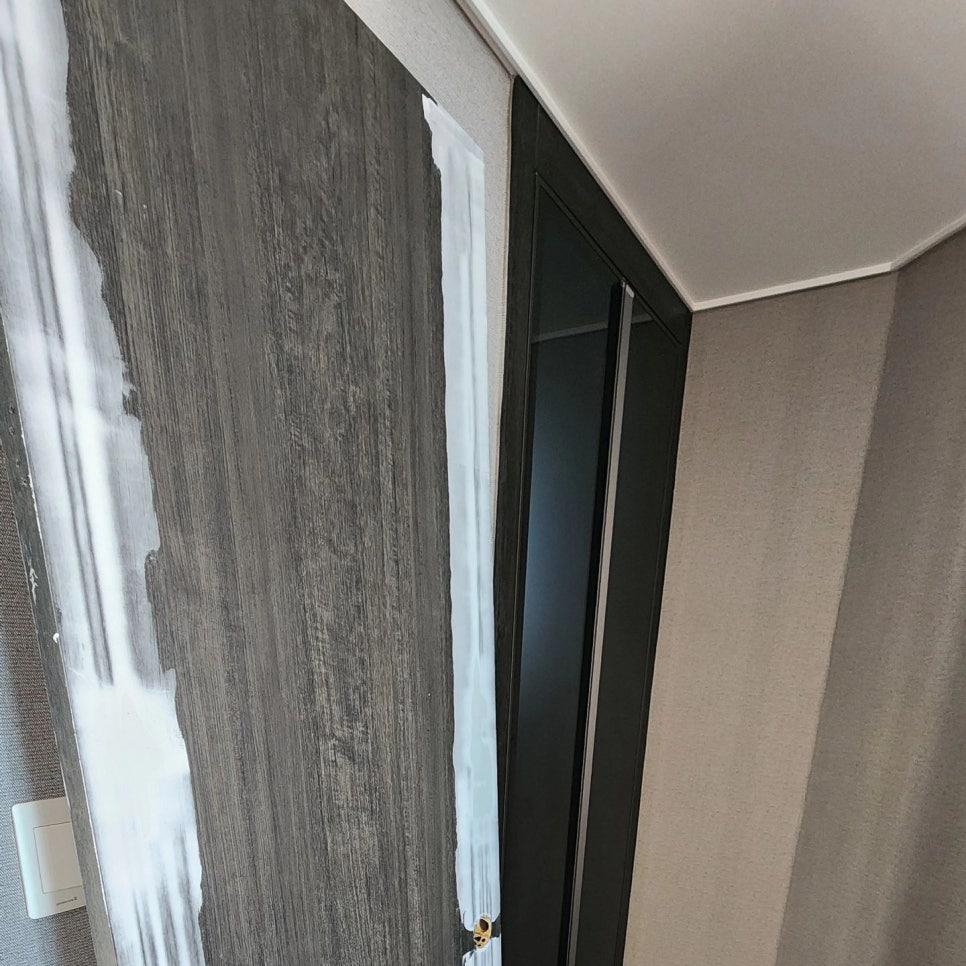 회색 목재 패턴 벽면과 검은색 도어의 경계 처리