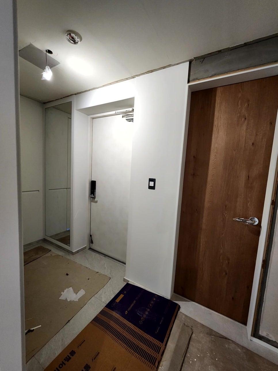 조명과 나무 문이 설치된 현관 공사 현장