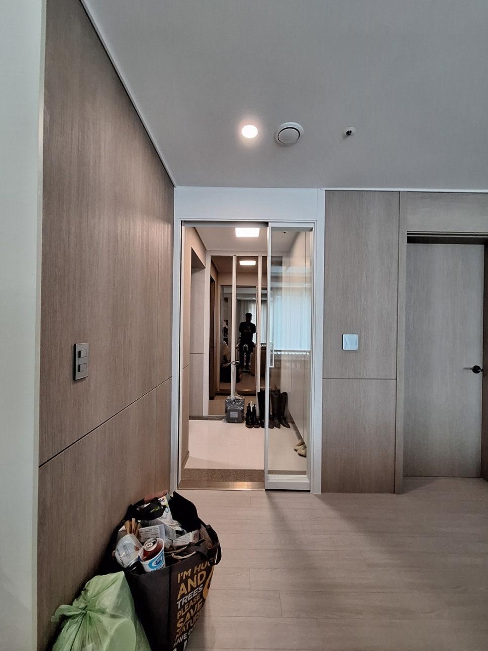 회색 톤 목재 마감과 유리 도어가 설치된 복도 전경
