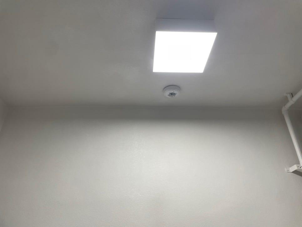 천장 조명과 흰색 배관이 보이는 실내 공간