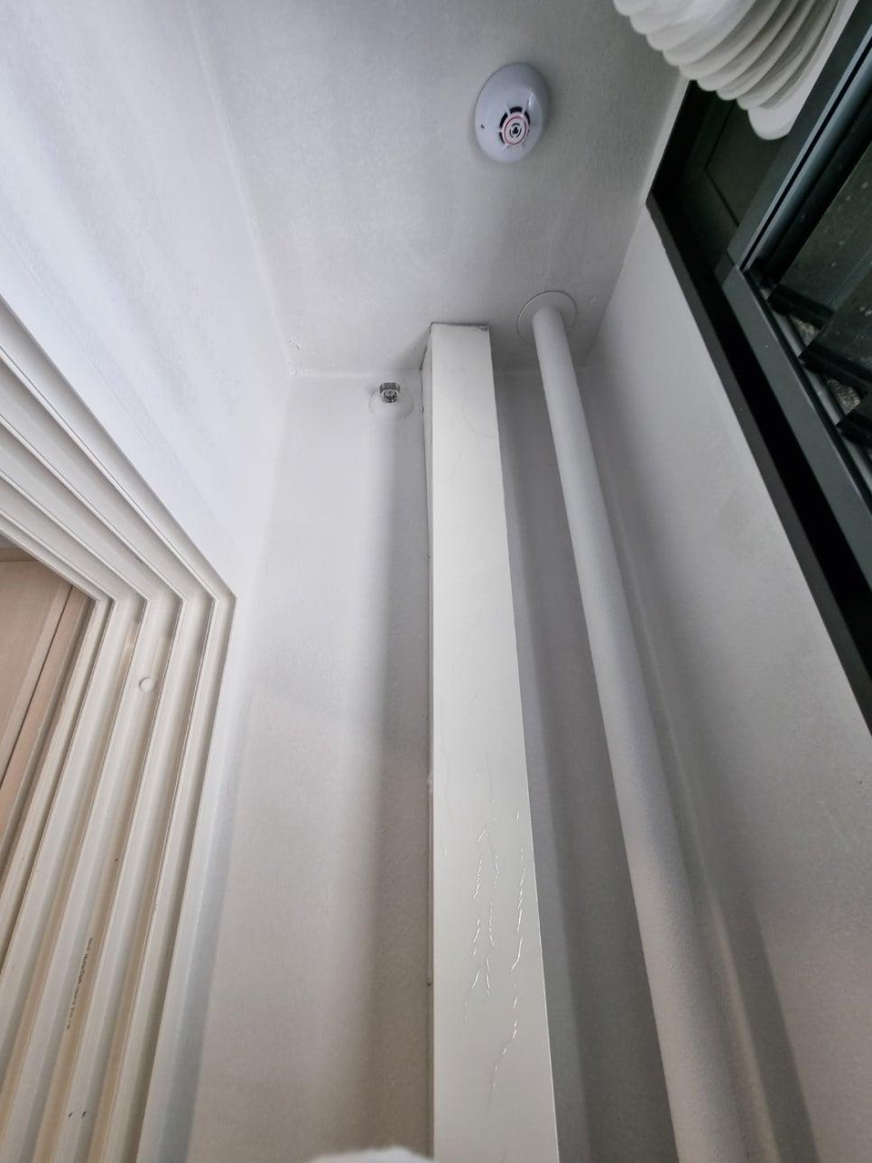 화재 경보기와 백색 PVC 파이프가 설치된 흰색 벽면