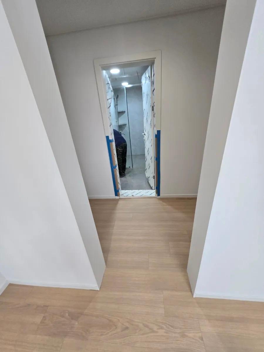 흰색 도어와 목재 바닥이 만나는 복도 구간