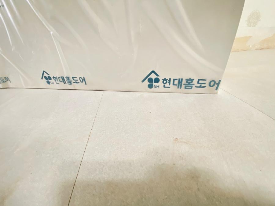 현대홈도어 로고가 인쇄된 포장지와 타일 바닥