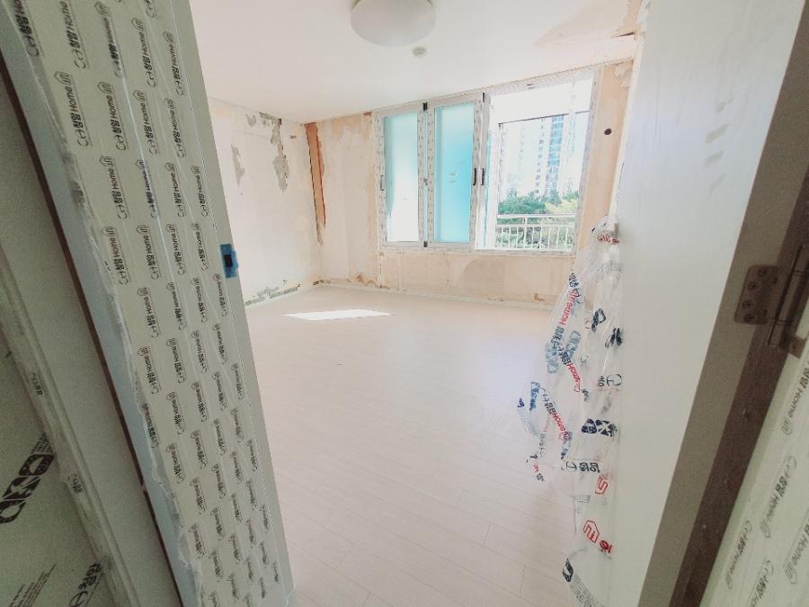 벽면이 벗겨진 방 내부와 흰색 타일 바닥