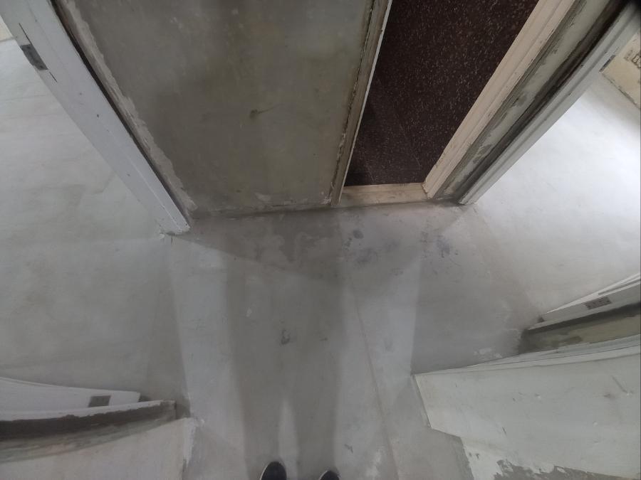 흰색 콘크리트 바닥과 회색 문짝이 보이는 복도